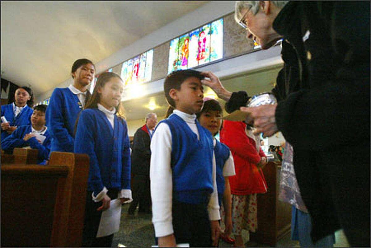 Richard Panela has his forehead marked with ash by Sister Nancy Anderson at the culmination of an Ash Wednesday service at St. Edwards Church. Anxiously awaiting her turn at left is Theresa Tran. Both are second-graders at St. Edwards Parish School in Seattle.