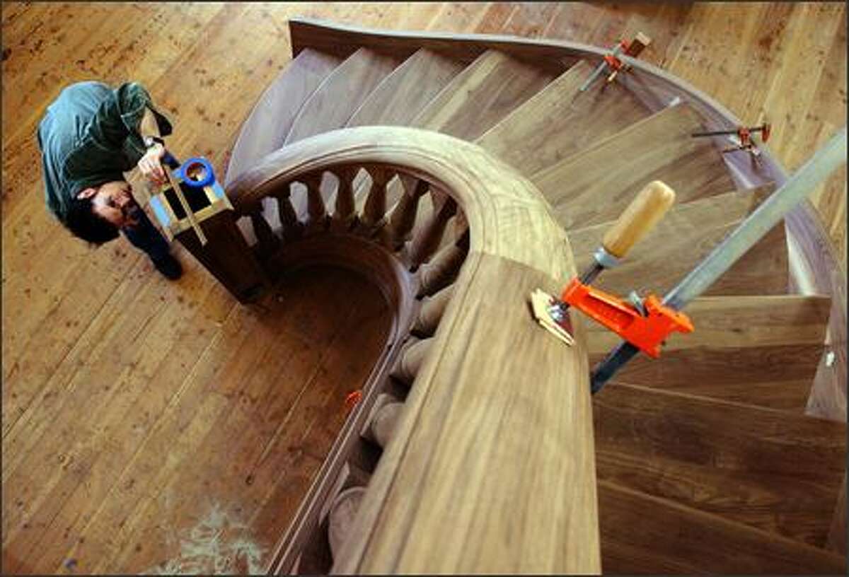 Paul Savino, lead designer and craftsman at Seattle Stair and Design, works on finishing the starter newel post on the "Carter" spiral staircase at the company workshop. The custom hand-built, 14-foot-high staircase is made from Black Walnut, weighs over a ton and has taken almost nine months to complete. When finished it will be installed in a Friday Harbor home.