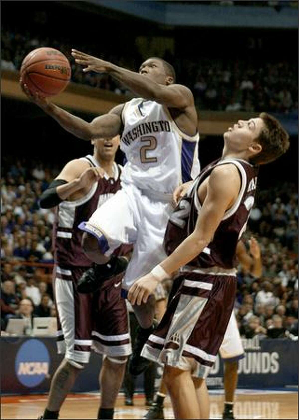 Nate Robinson (2) blows by Montana's Matt Martin, right, in the first half of the Huskies-Montana game. Robinson was relatively quiet with just nine points but did have a team-high five assists.