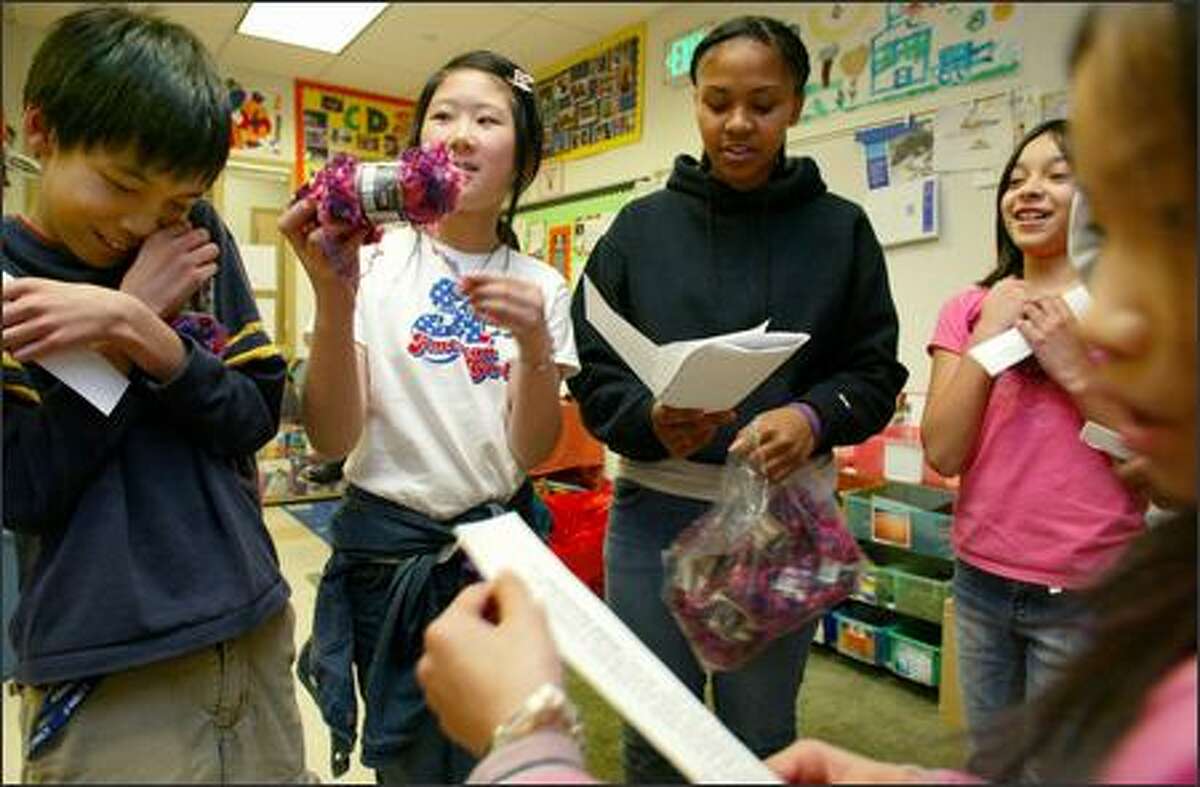 Garfield High School student Marita Phelps, center right, holds her notes as she leads a group of Maple Elementary School students in a role-playing exercise recently to teach them about how microloans help people in developing countries pull themselves out of poverty. The students, from left, Eddy Liu, Winnie Kwong, Vanessa Garcia and Khanh Phan exchange pretend money for pretend chickens. Phelps learned about microloans on a recent trip to Guatemala with Global Visionaries.