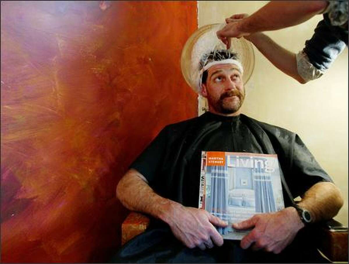 Stylist Patrick Bertels at work on the very thick hair of Bellingham contractor John Harris. Harris was chosen to be the makeover subject of five Bellingham-area gay men as part of a Queer Plan for the Straight Man benefit.