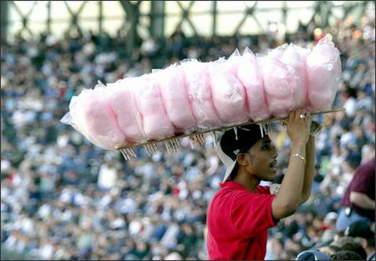 Vendor Charles Sparks works the stands with a load of cotton candy. He had a full house at Safeco Field yesterday to buy his goods. And that included plenty of prime customers –- young fans -– among them.