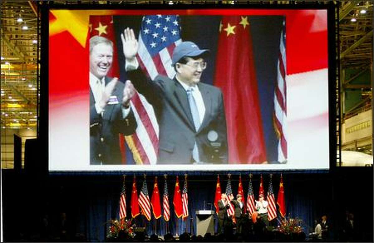 Wearing a Boeing cap, Chinese President Hu Jintao waves to workers Wednesday at the Everett plant. At left, Boeing exec Alan Mulally.