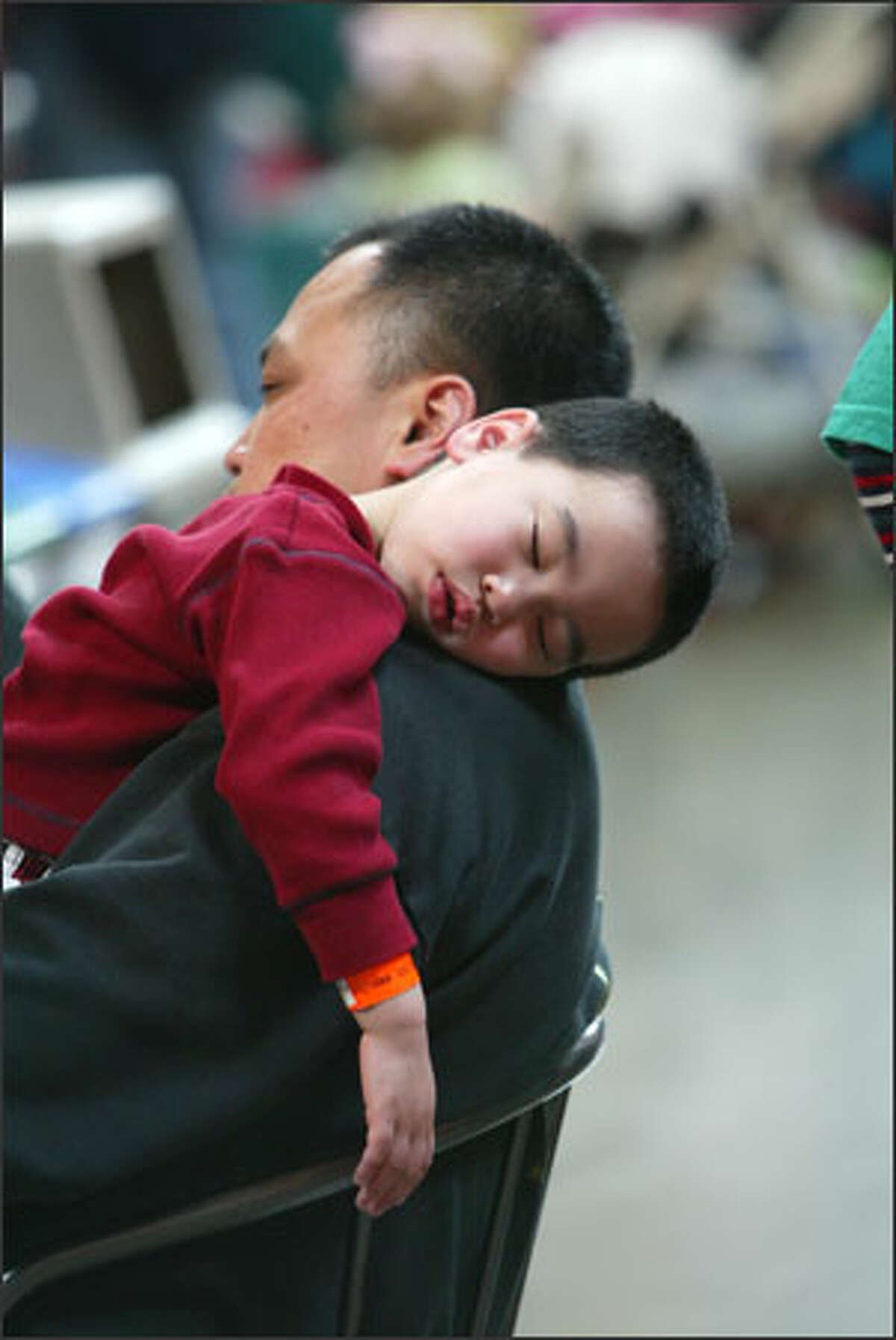 Shing Chin holds his sleeping son, Carson, 3, while watching a dance group perform at the Center House.