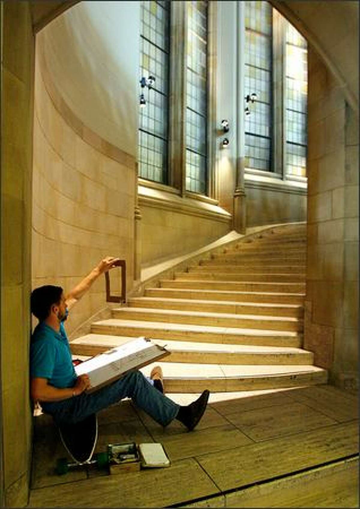 University of Washington student Max Lang holds up a cardboard viewfinder as he sketches the steps and columns of the grand staircase inside the Seattle campus's Suzzallo Library.