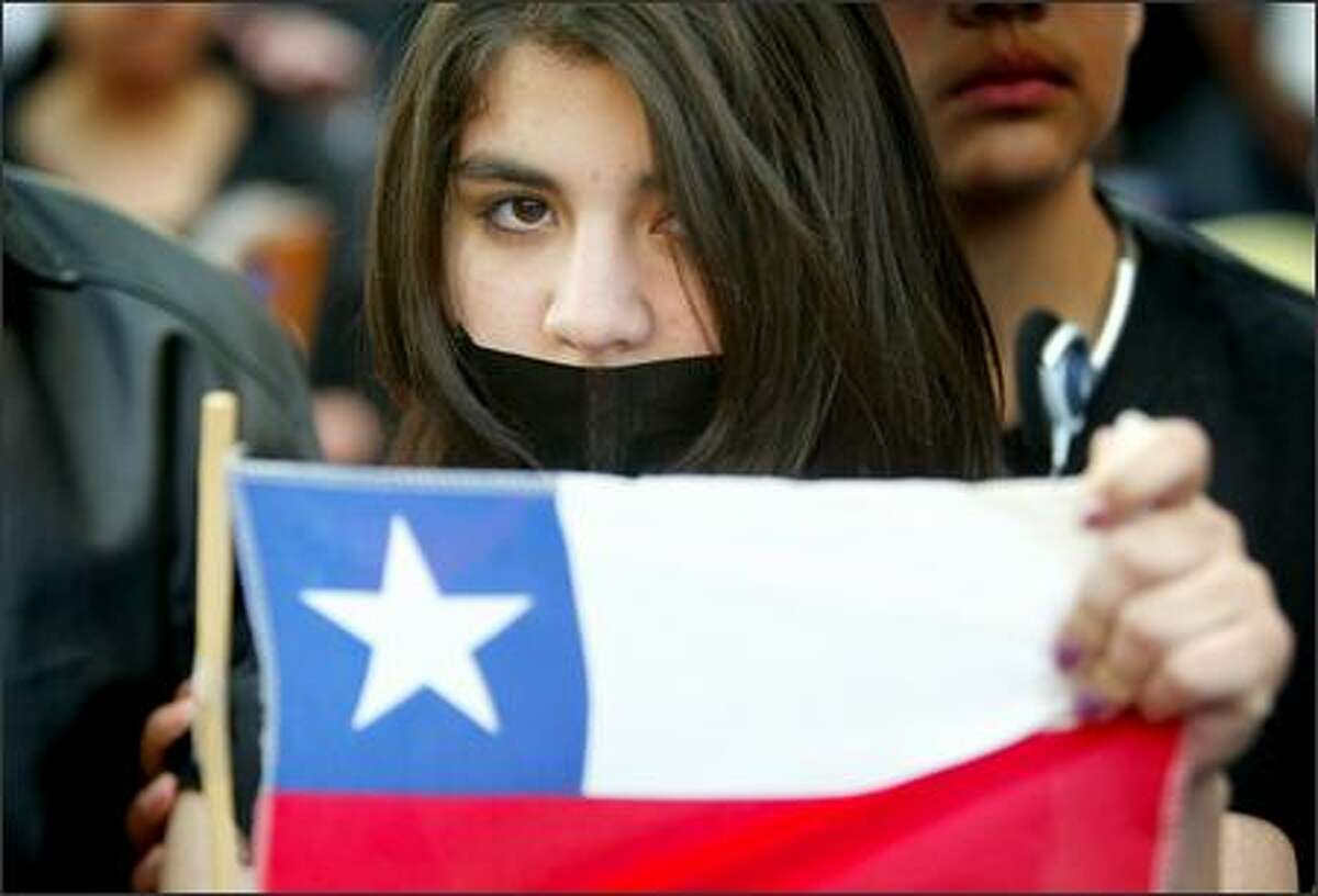 Verna Faundez, 15, from Chile, holds her country's flag during a mostly silent and solemn immigrant rights rally in downtown Seattle.