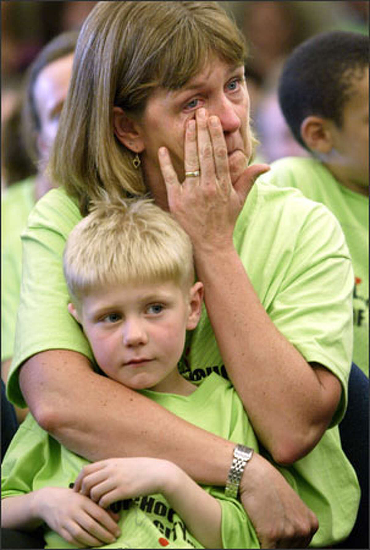 Lynne Butz tears up while holding onto her son, Simon, 7, at a Seattle School Board meeting. More than 200 parents and students turned out to protest the district's plan to close 10 schools.