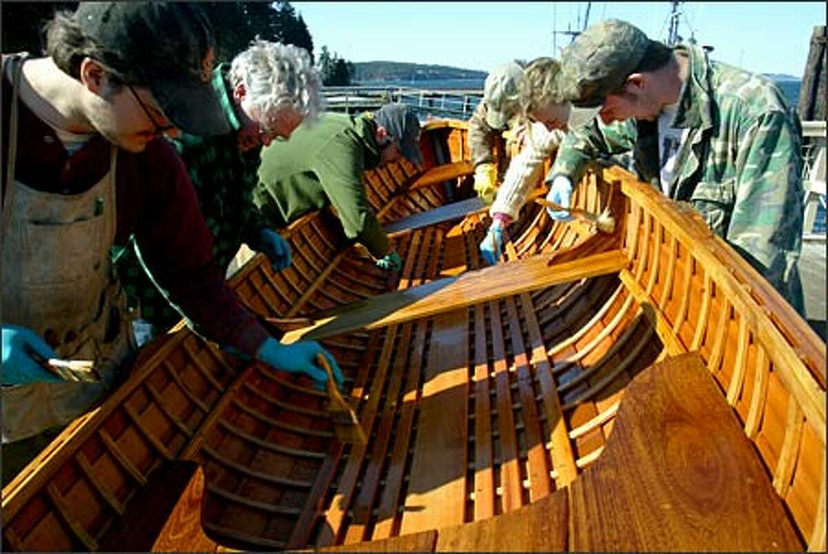 Students apply "boat sauce," a mix of oil and varnish, to a 12-foot Grandy skiff.