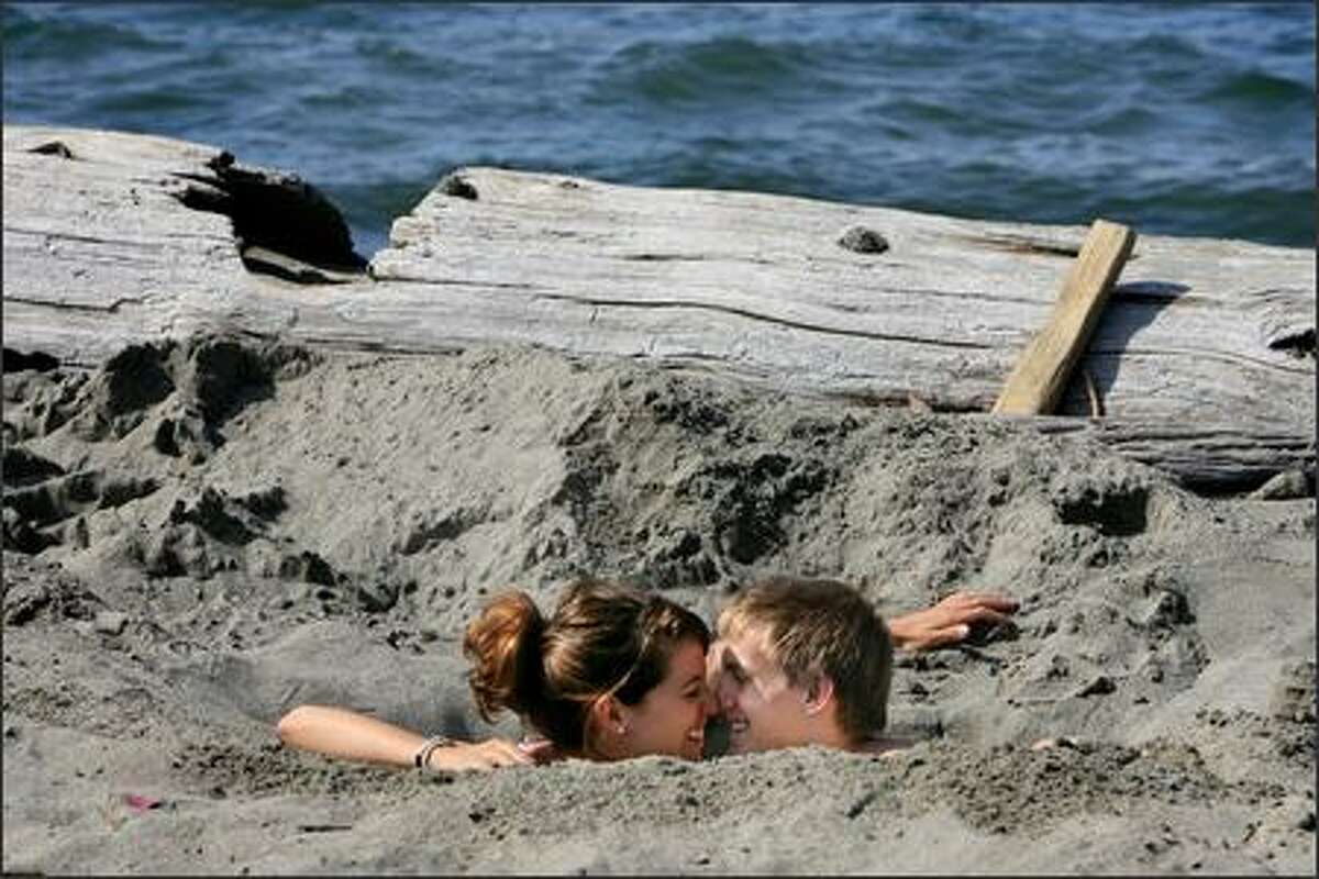 Sarah Vacanti of Seattle and Luke Golesh of Denver, both 20, enjoyed Monday's pleasant weather -- not to mention each other's company -- by digging a hole in the sand at Alki Beach Park in West Seattle. Both finished their sophomore year at Gonzaga University on Friday and decided to get an early start on summer.