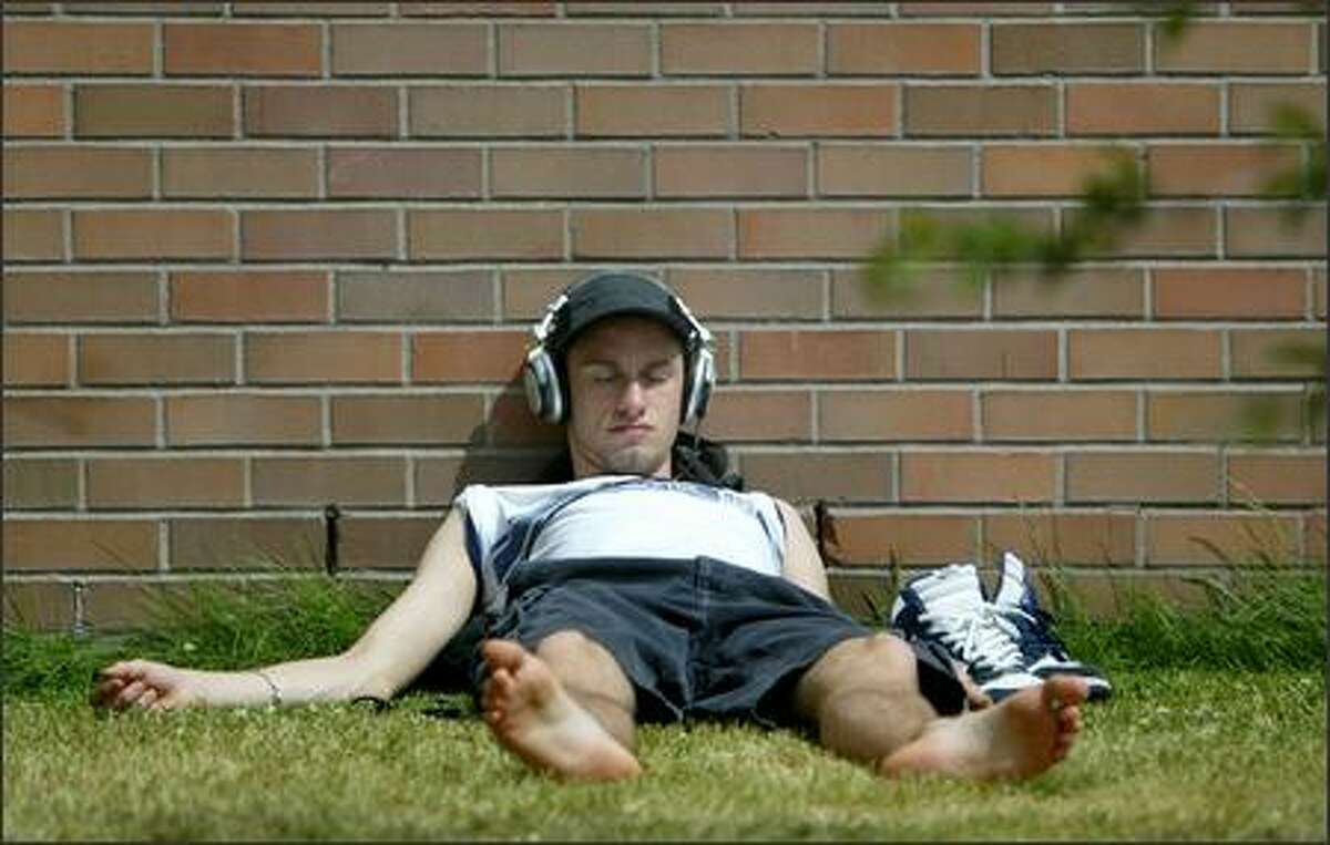 Julian Prindle, a second-year student at Seattle Central Community College, takes a nap in the sun during a break in his schedule on the Capitol Hill campus. As the economy continues to strengthen, enrollment is down because fewer people need retraining after losing a job. But that good news is bad news for Central and North Seattle community colleges, which are planning to cut their budgets to make up for the loss in tuition.