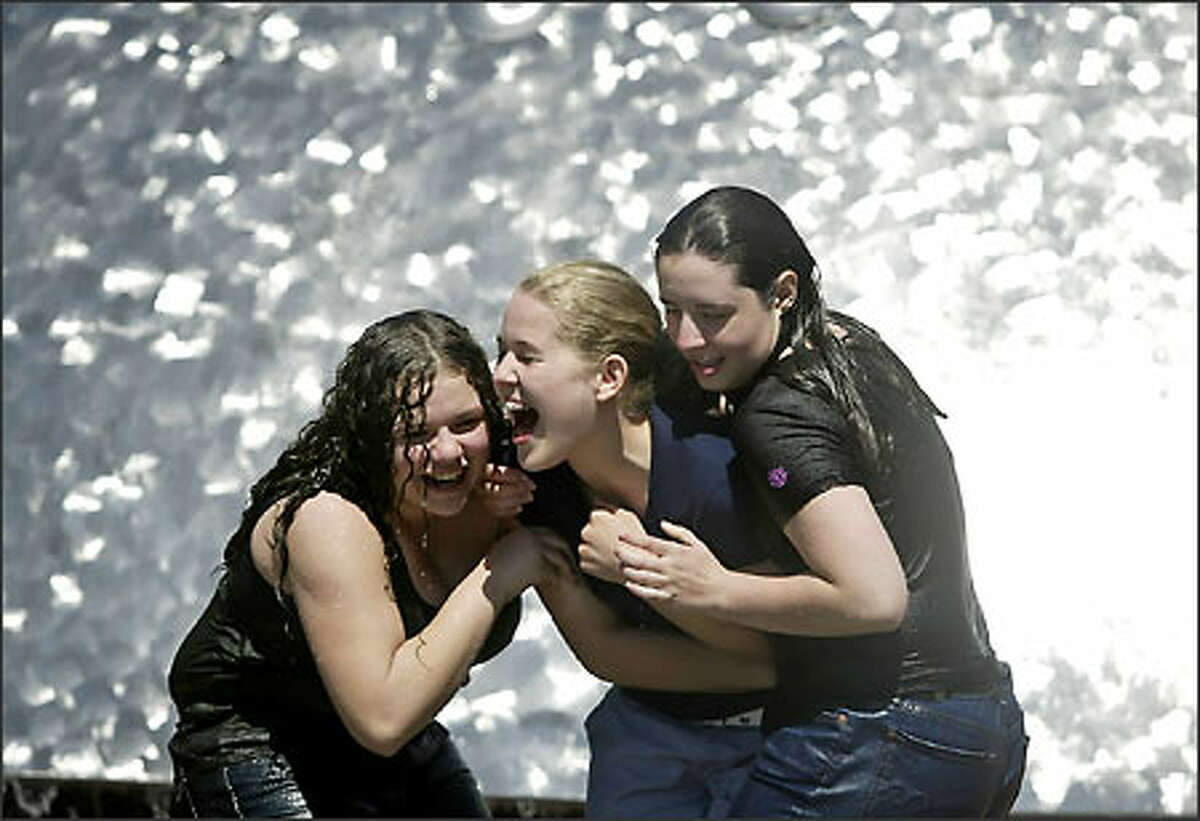 Dripping wet Chyna Copeland, left, and Kelsey Morton, drag a very dry Mary Elizabeth Howard, center, all of Redmond, for a dousing in the International Fountain at the Seattle Center on Tuesday.