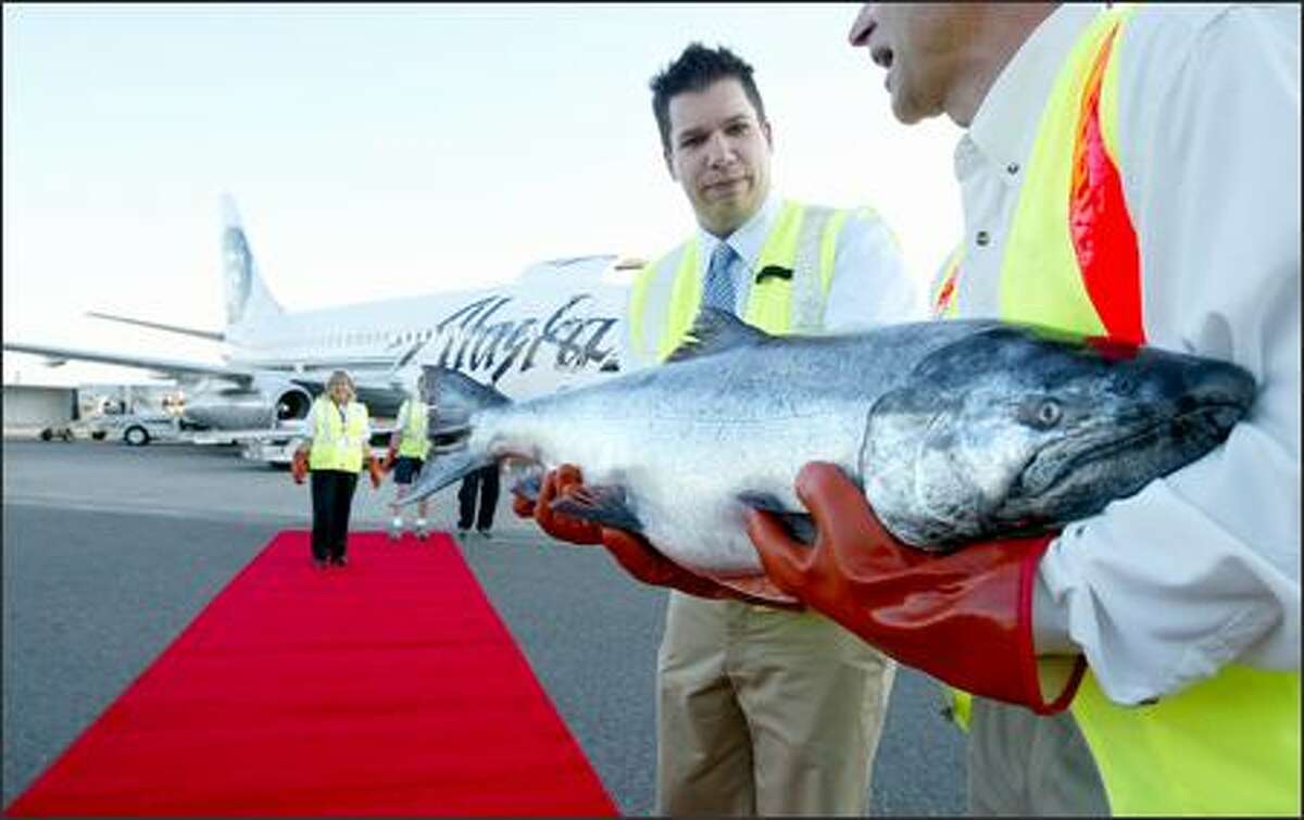 Alaska Airlines cargo manager Matt Yerbic passes a Copper River king salmon to Tom Sunderland of Ocean Beauty Seafoods. The prized fish could fetch record prices this year.