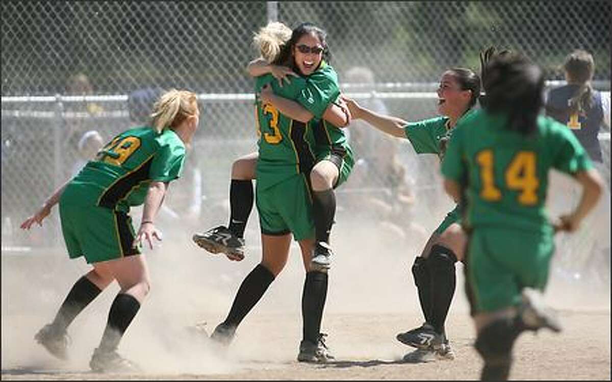 Blanchet's Adrianne Loyola jumps into the arms of pitcher Aly Schoonover after the final out in the Braves' 8-5 win over Bellevue in the 3A Sea-King District fastpitch playoffs.