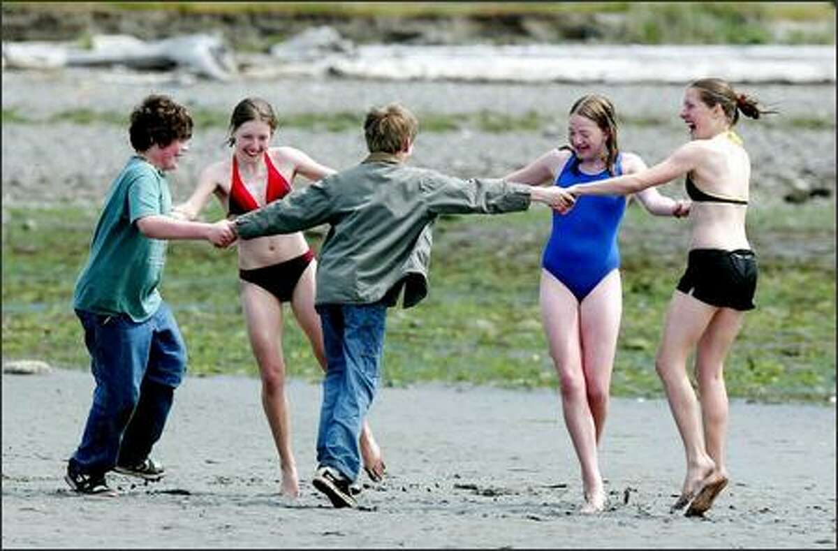 Dancing on the beach after a dip into Kilisut Harbor are twins Geneva and Hillary Pritchett with their friend Barbara Seely, 15-year-olds from Bainbridge Island.