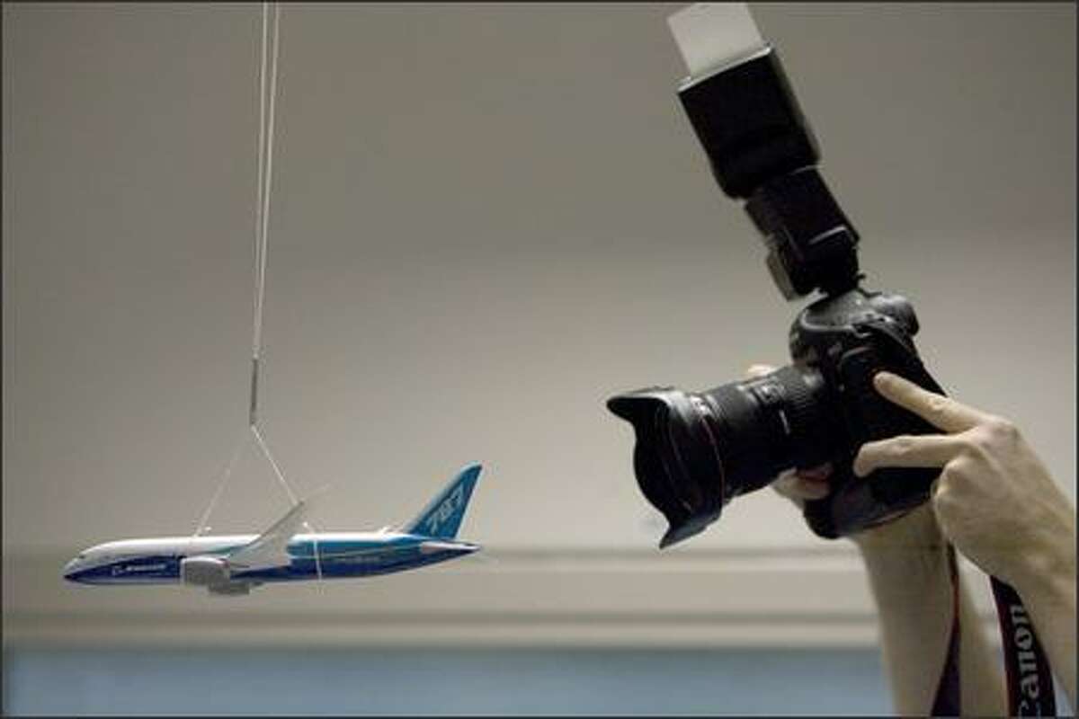 One of the dozen or so still photographers visiting Boeing's avionics integration lab photographs a model of the 787 hanging.