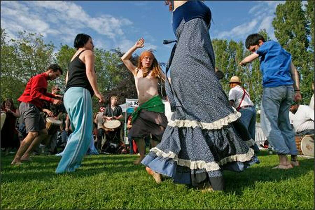 Northwest Folklife Festival-goers dance to the beat of more than two dozen drummers near the International Fountain during the annual Memorial Day weekend celebration at Seattle Center.