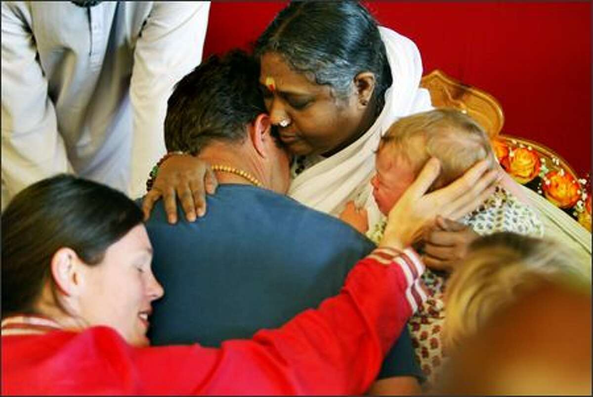 Deedee, left, and Chris Almida from Stanwood, and their sons London, 3, and Micah, 9 months, get a hug from Amma. "It's beautiful. It's pure love. It feels good and warm." said Deedee. The "hugging saint" Mata Amritanandamayi, known as Amma ("Mother"), appeared at Seattle Center on Thursday.