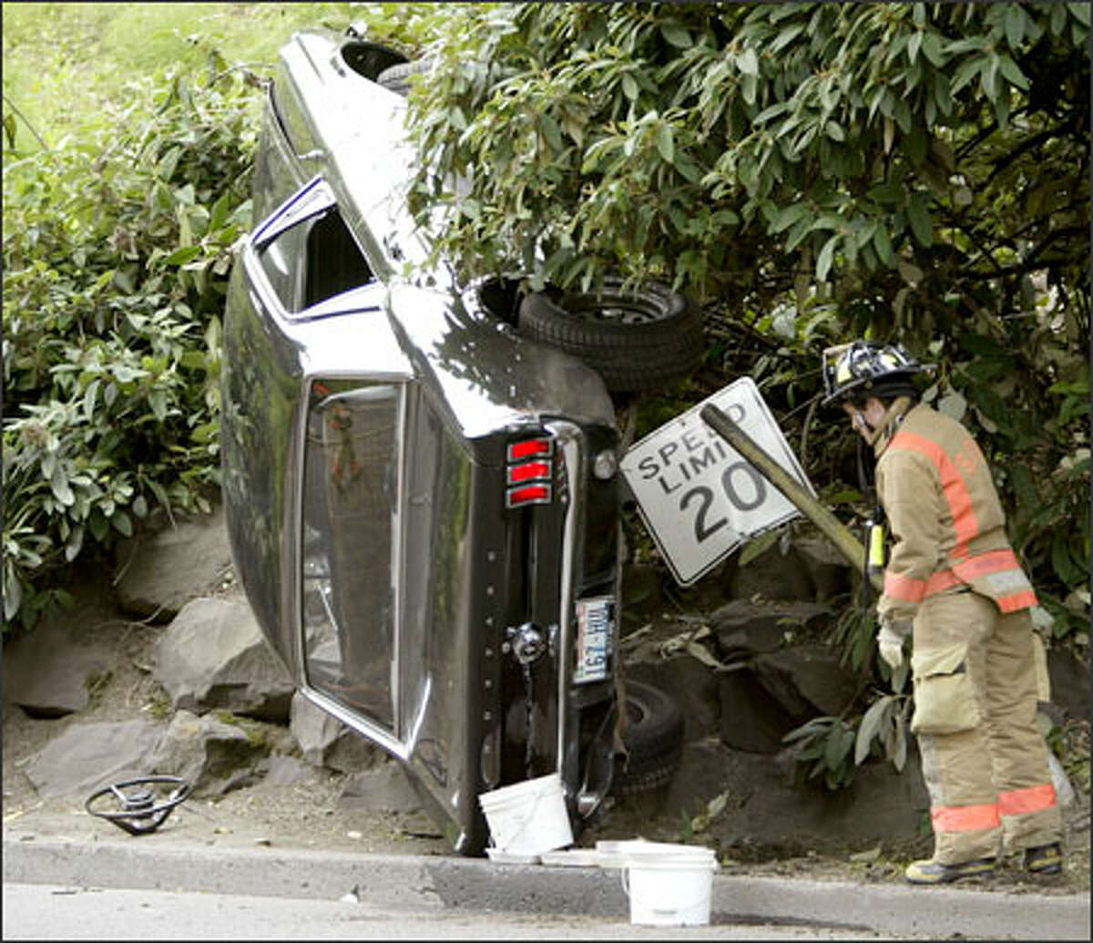 A Seattle firefighter surveys the scene of an accident near the University of Washington. A driver, who declined to give his name, lost control of his car and crashed into a rock retaining wall when his steering wheel came off on Pend Oreille Road at the northeast entrance to the campus.