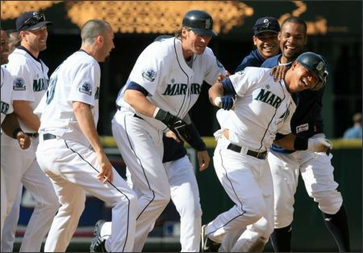 Jose Lopez, right, is mobbed by teammates after connecting for a game-winning double against Boston at Safeco Field on Wednesday. The Mariners won 2-1 in 11 innings to sweep a three-game series against the Red Sox, who have baseball's best record.