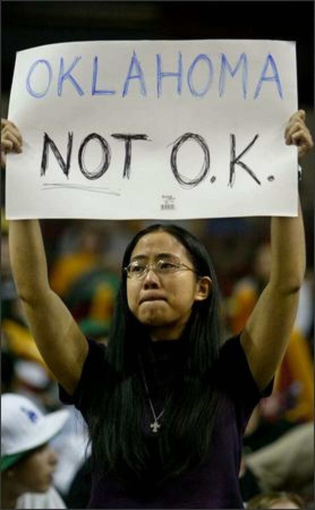 Seattle Storm season ticket holder Becky Chow holds up a sign protesting the sale of the team and the Seattle SuperSonics as other fans cheer during a game against the Sacramento Monarchs. The Monarchs won, 74-61.