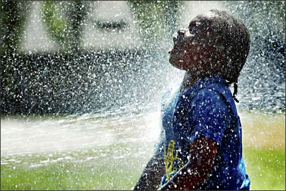 Ivory White, 8, cools off at a fountain in Seattle's Pratt Park. He visited the park yesterday with other children from Yesler Community Center.