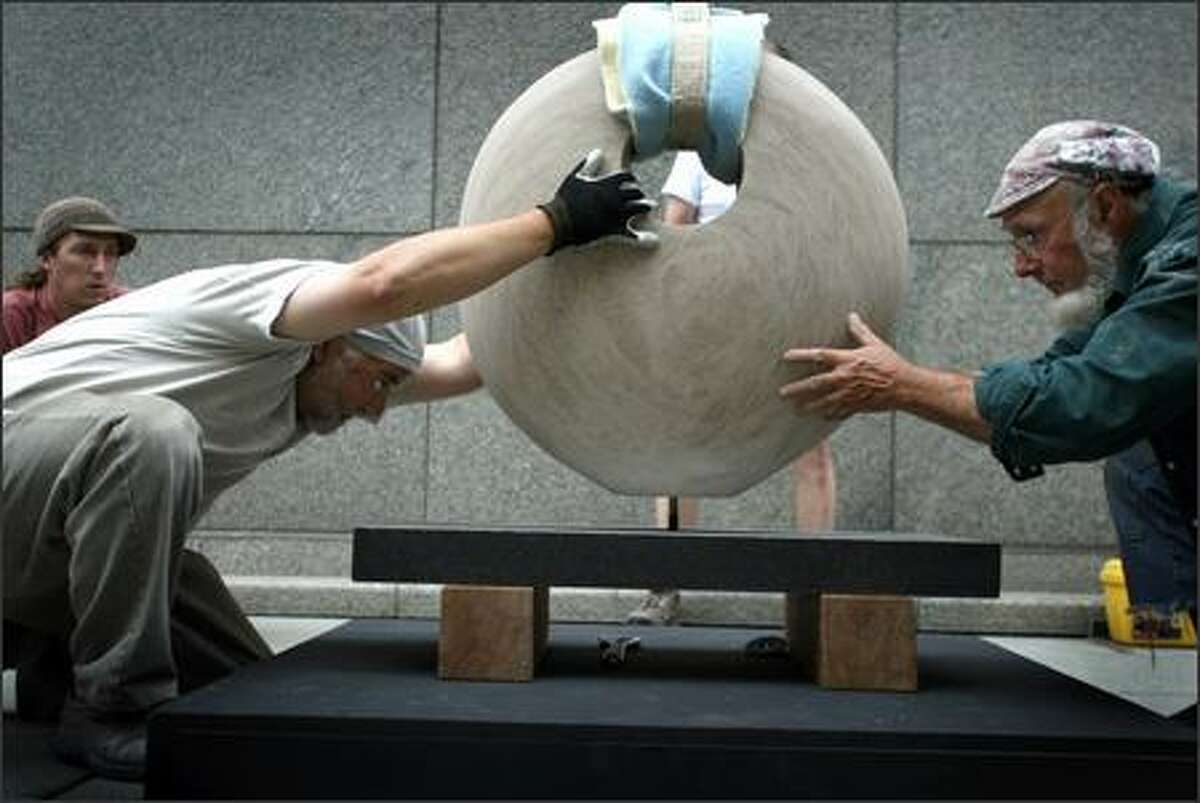 Artist Brian Berman, left, is helped by artist Pete Welty on Tuesday as they install Berman's stone sculpture Genesis on the walkway next to Benaroya Hall. The work is part of the West Edge Sculpture Invitational exhibit; 29 works were installed along Benaroya Hall and Harbor Steps.