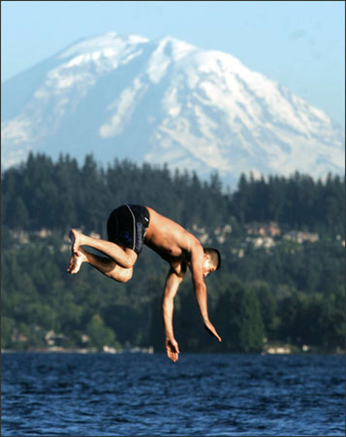 Moises Delgadillo dives off the swimming dock at Warren G. Magnuson Park in Seattle at dusk. Local temperatures hit the 80s this past week.