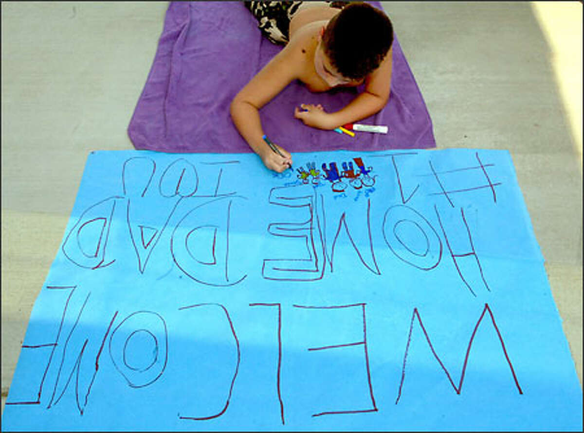 Julian Chavez, 10, works on a poster in Moses Lake to welcome home his stepdad, Spc. Ben Candanoza. The picture shows Julian standing between his mom and stepdad, with two of his brothers.