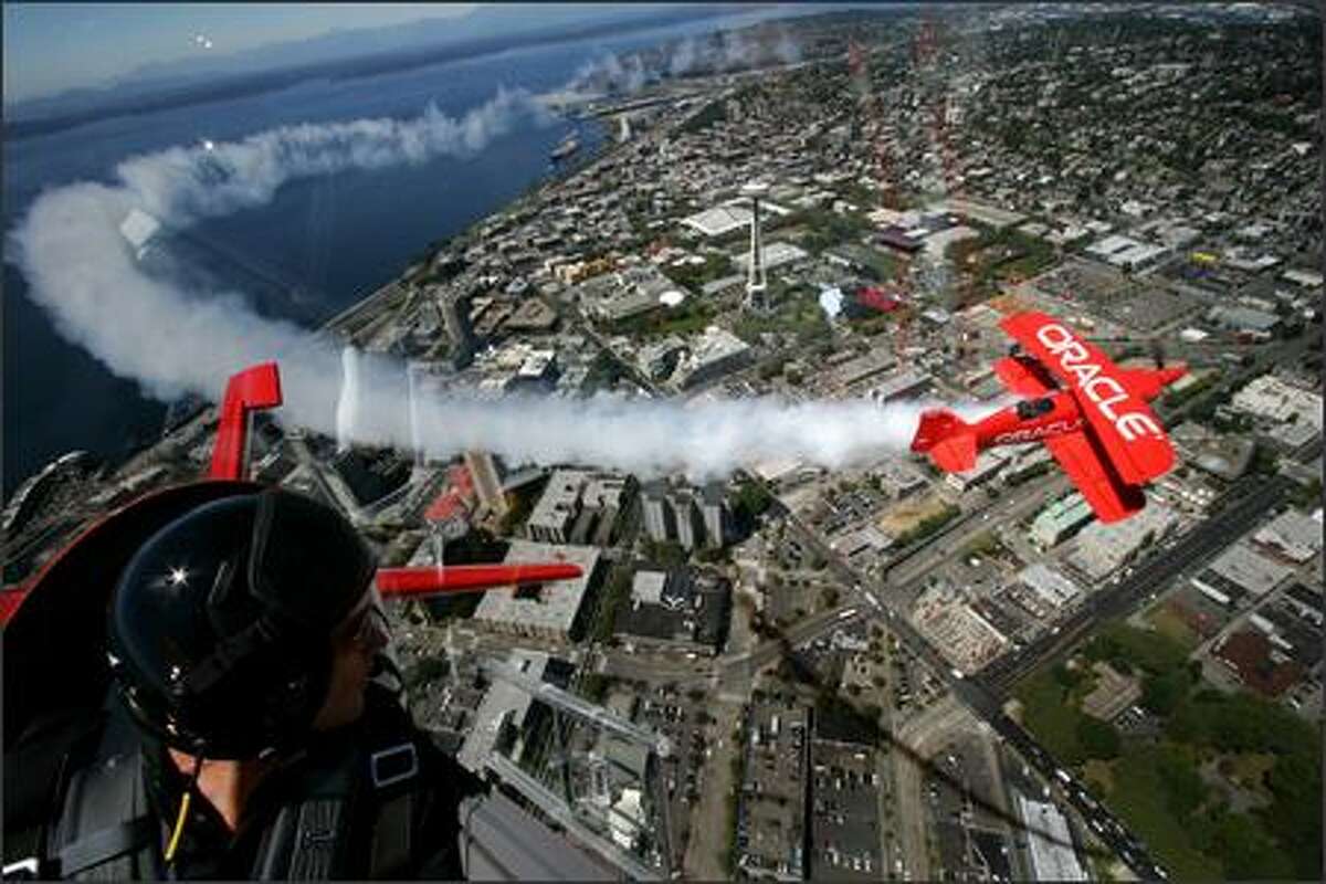 Team Oracle pilot Eric Tucker, left, watches as his father, reknown aerobatic pilot Sean Tucker fly in formation as they practice over Seattle on Thursday August 2, 2007. The planes are in town and are practicing and preparing their show for Seafair.