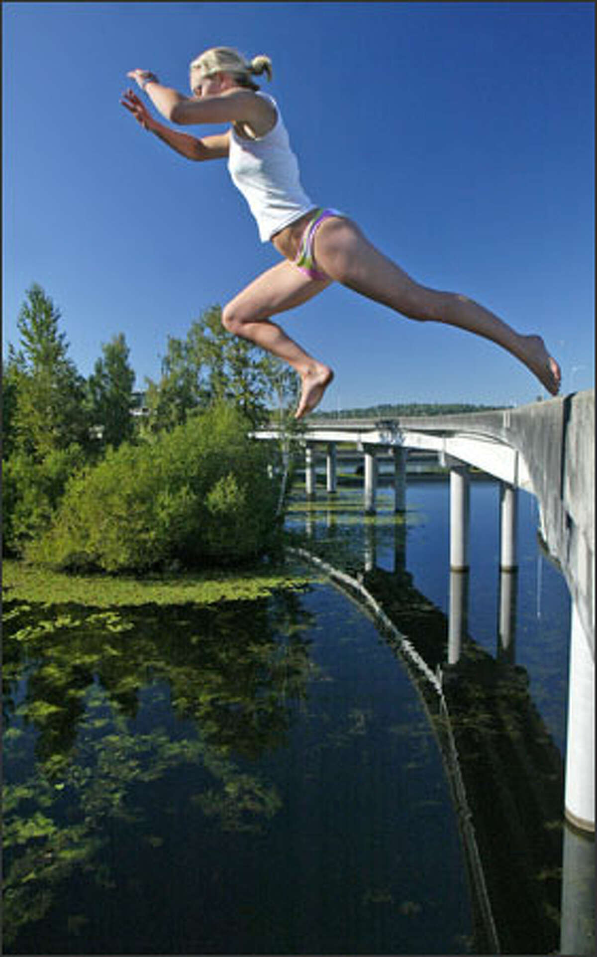 Alex Merrick takes a flying leap off a closed and unused section of the state Route 520 Bridge into the cool water of the Washington Park Arboretum below. The bridge is a perennially popular spot for people seeking relief from the heat after summer officially arrives.