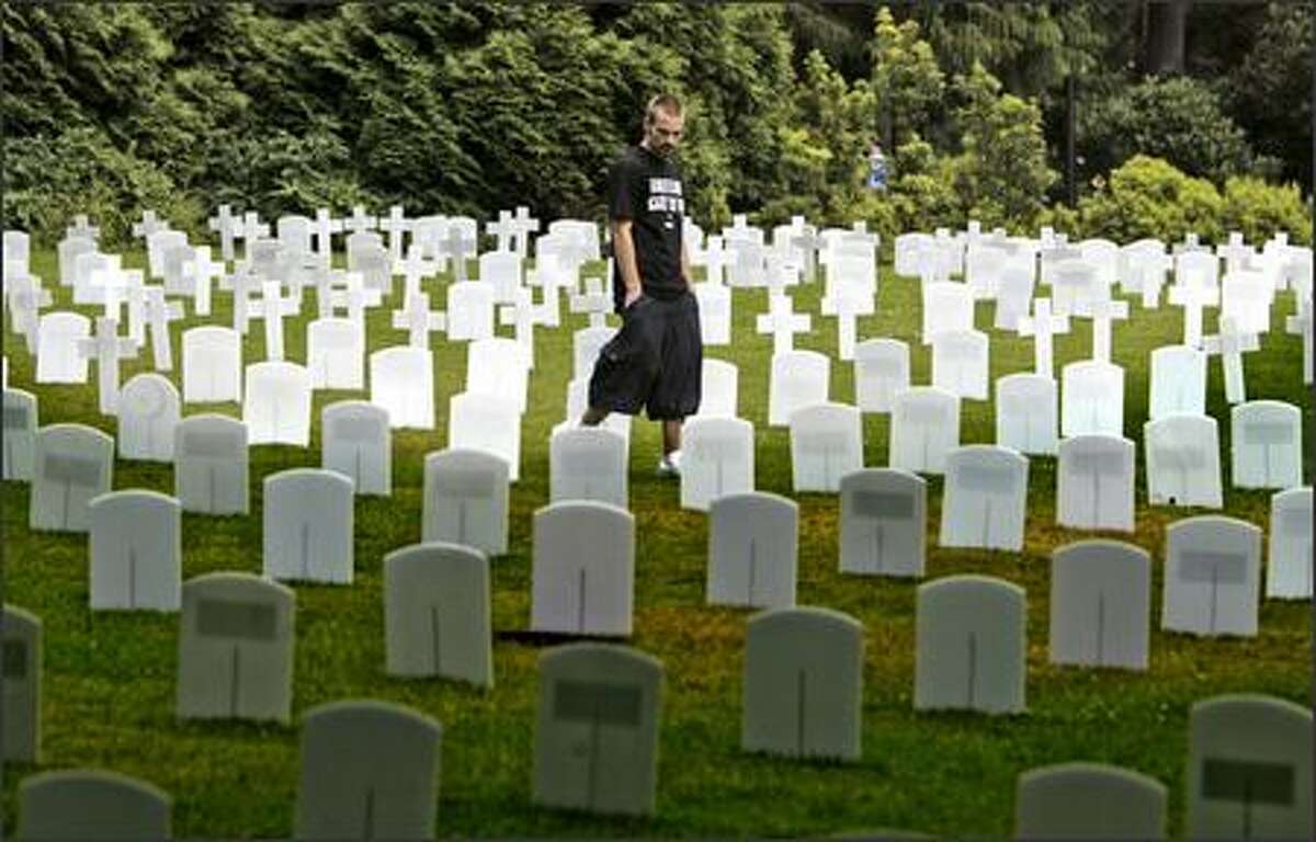 Army veteran Steve Mortillo searches for fallen friends among grave markers on display outside of the HUB at the University of Washington on Thursday. Mortillo, of New Jersey, served in Iraq in 2004-05. He is now a member of Iraq Veterans Against the War and was participating in a Veterans for Peace convention. Mortillo said the names of 12 of his friends who were killed in Iraq were on the markers.