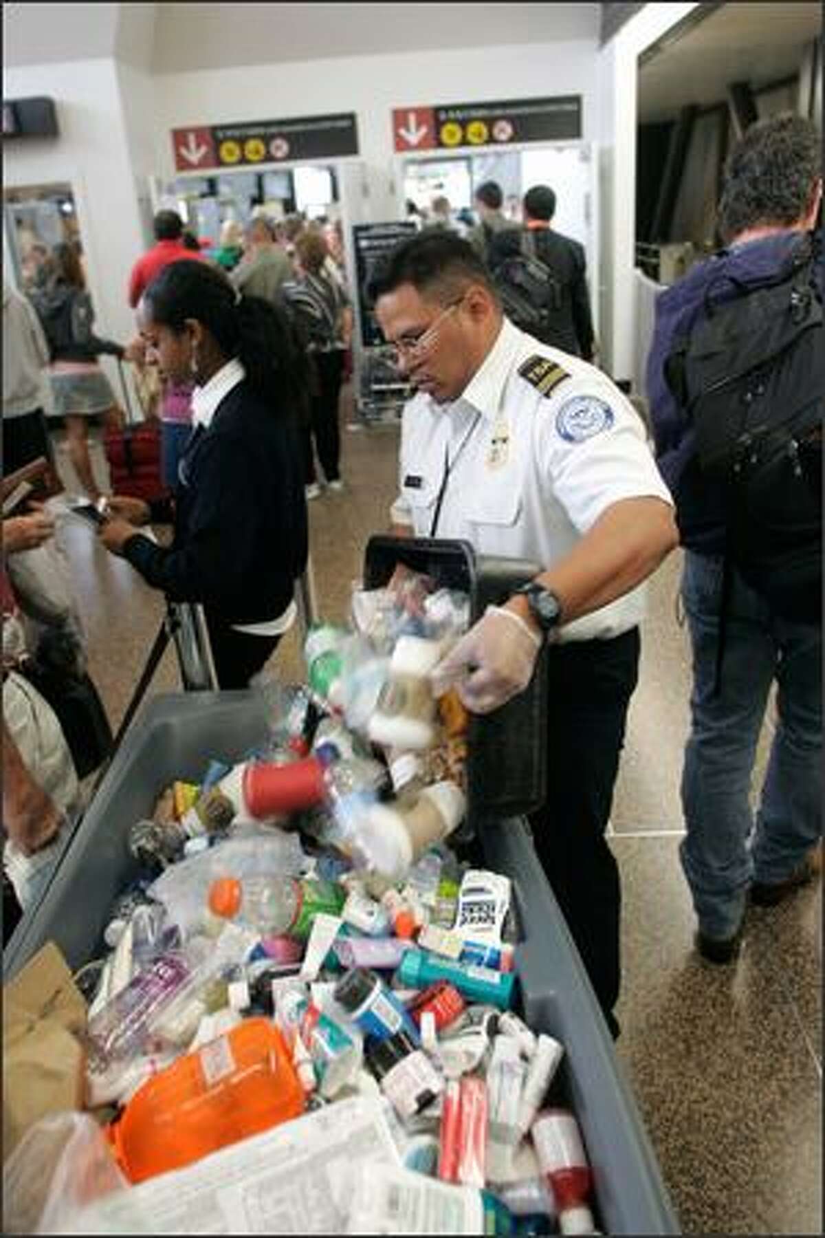 A Transportation Security Administration employee dumps a box containing items no longer permitted on board aircraft -- including beverages, toothpaste, shampoo, deodorant sticks and other such liquids and gels. New restrictions on carry-on luggage were imposed Thursday morning after British authorities thwarted a terrorist plot to blow up airliners headed for the United States using liquid explosives smuggled onto flights.