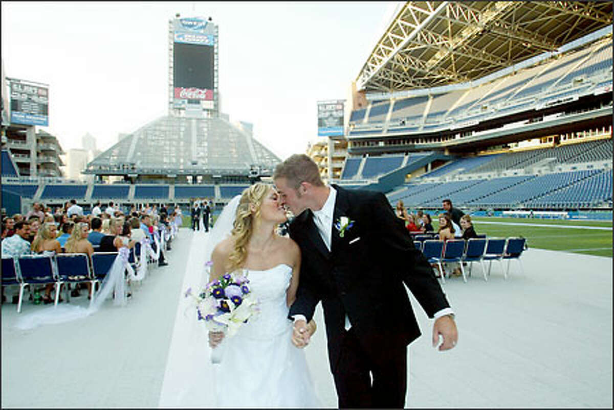 Chris and Alexis kiss as they walk up the aisle after the ceremony. The newlyweds are so into the Seahawks that they planned to postpone their honeymoon for a day so they could watch Monday night's preseason game against the Green Bay Packers.