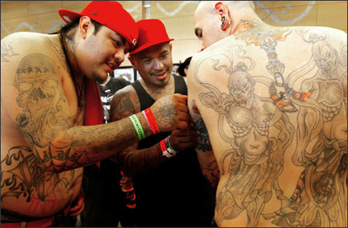 From left, tattoo artists Kilo (no last name given) and Juan Carrillo of Yakima, Wa., examine J.J. Moiso's body art after participating in the "Large Black and Gray" contest Sunday at the Seattle Tattoo Convention. The event drew an estimated 6,000 people to the Seattle Center over the weekend.