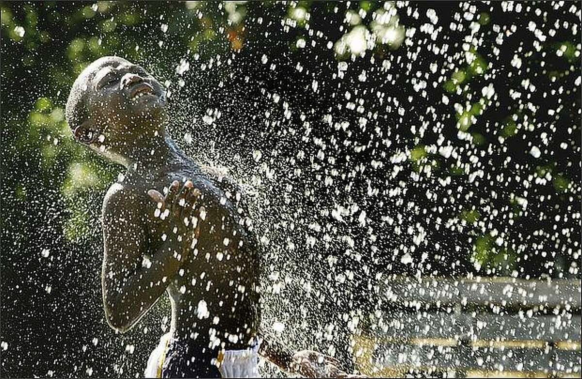 Damunique Pierce, 6, of Seattle, embraces the spray from a fountain at Pratt Park in Seattle, as temperatures at Sea-Tac Airport hit a record 89 degrees.