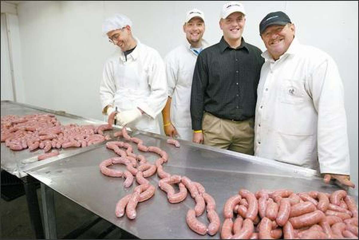 (Editor's Note: This caption has been altered. The original version misspelled the Banchero family name.) Erik Carlson, far left, cuts a sausage at Rainier Valley's Mondo & Sons, which plans to expand. Family owners, from left, are Angelo and Mario Banchero and father Lew.
