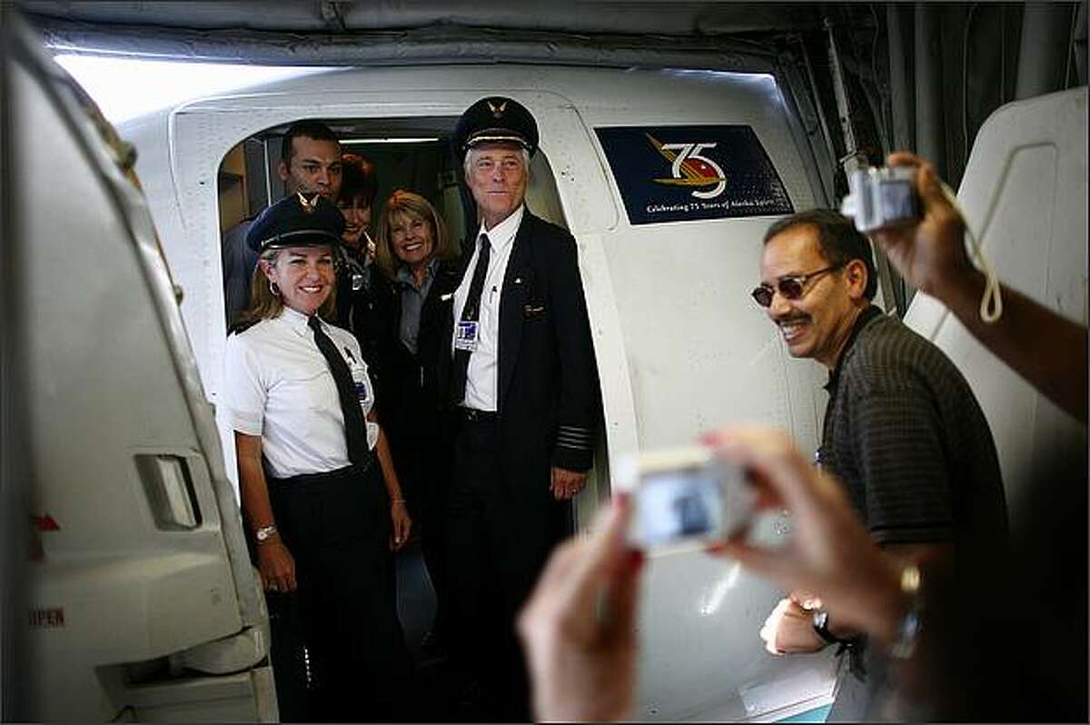 Guests take pictures of Claude Tirman, his daughter Dana Haines, left, and the flight crew on Tirman's final flight as an Alaska Airlines pilot. Tirman retired from the airline after 27 years with his final flight from California to SeaTac.