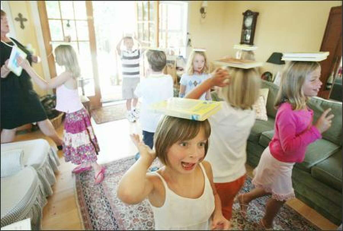 At Mrs. DeGroot's Wallingford Charm School, children walk with Nancy Drew books on their heads, aiming for statuesque posture. Frances Foody, 7, front, is about to lose her book as she heads toward her goal, a jar of candy. Dawn DeGroot is at the left.