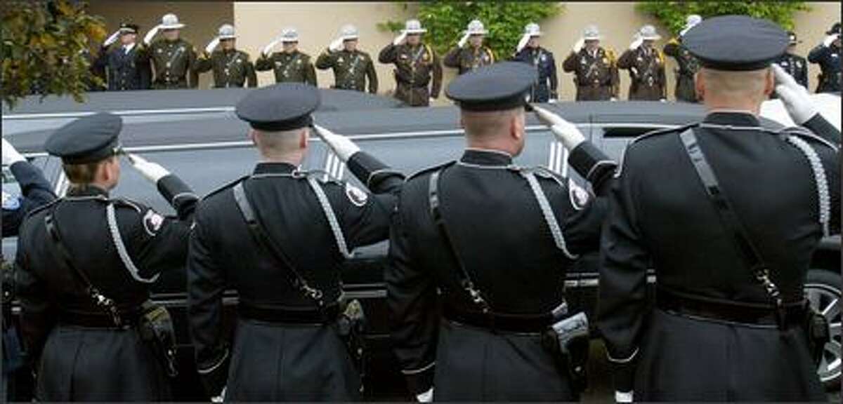 As officers salute, the hearse arrives at the memorial service for slain Brier Police Officer Eddie Thomas at the Westgate Chapel in Edmonds on Wednesday. Thomas died while responding to a medical emergency call at the home of former Brier Mayor Gary Starks. Cause of death is pending further investigation.