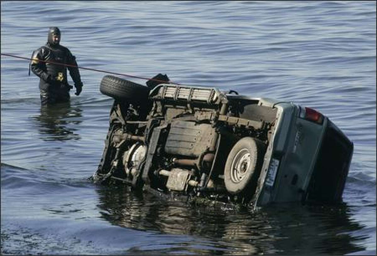 A Seattle Police officer inspects a Ford Explorer that flew off Alki Avenue in West Seattle and landed in Elliott Bay, killing two teens and injuring four.