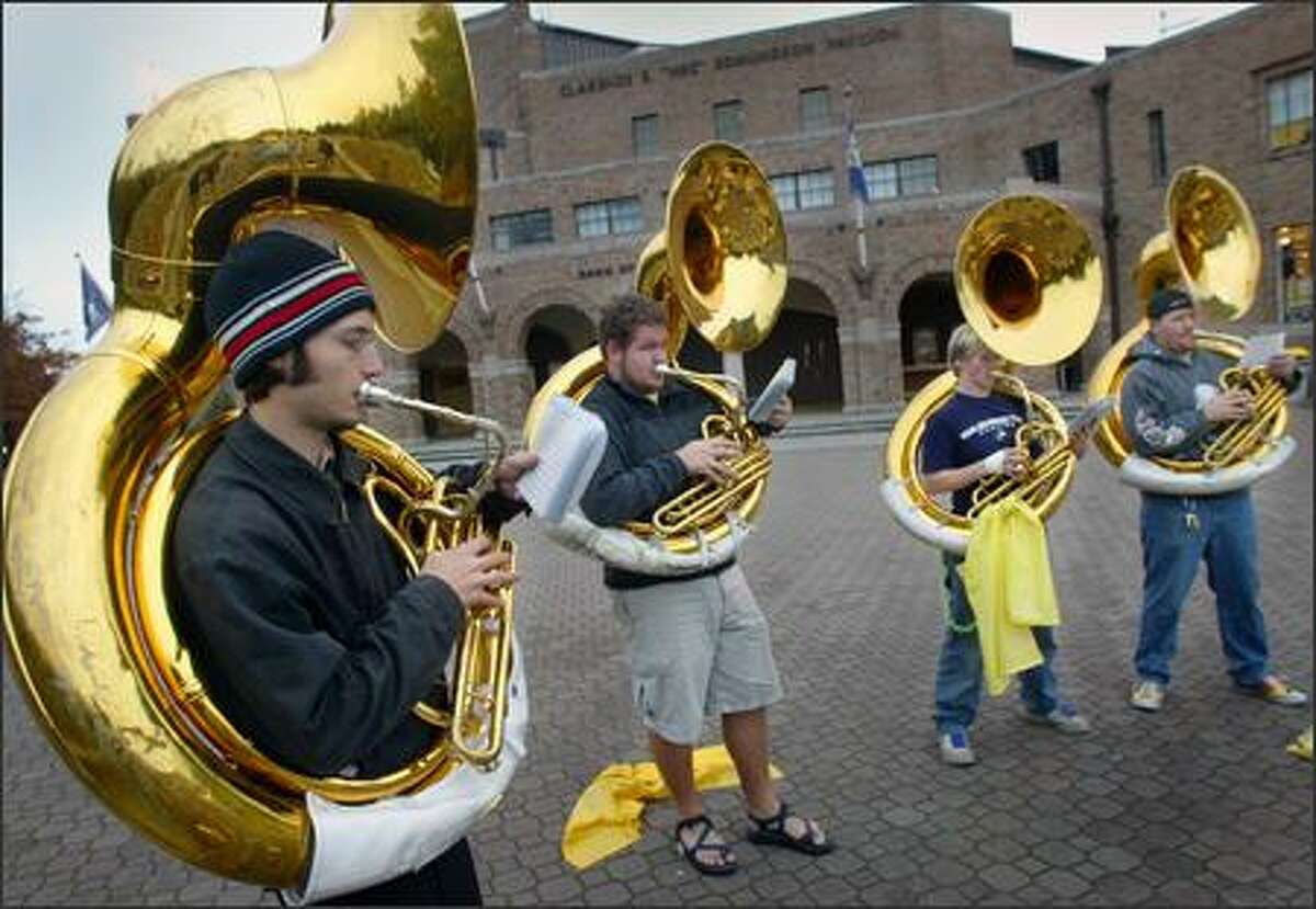 Members of the University of Washington marching band's brass section -- sousaphonists, from left, Peter Daniell, Ian Buchanan, Val Scrivner and Chris Buol -- practice yesterday in front of Hec Edmundson Pavilion. The marching band is a 240-member ensemble that adds energy to UW sporting events. The band is celebrating its 75th anniversary this school year.