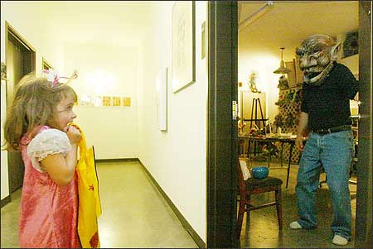 Gretta Woodall, 5, gets quite a start as artist Roger Wheeler greets her in a troll mask he made at the Tashiro Kaplan Artist Lofts on Halloween. Gretta lives there with her parents, George Woodall and Marina Shubina Woodall.