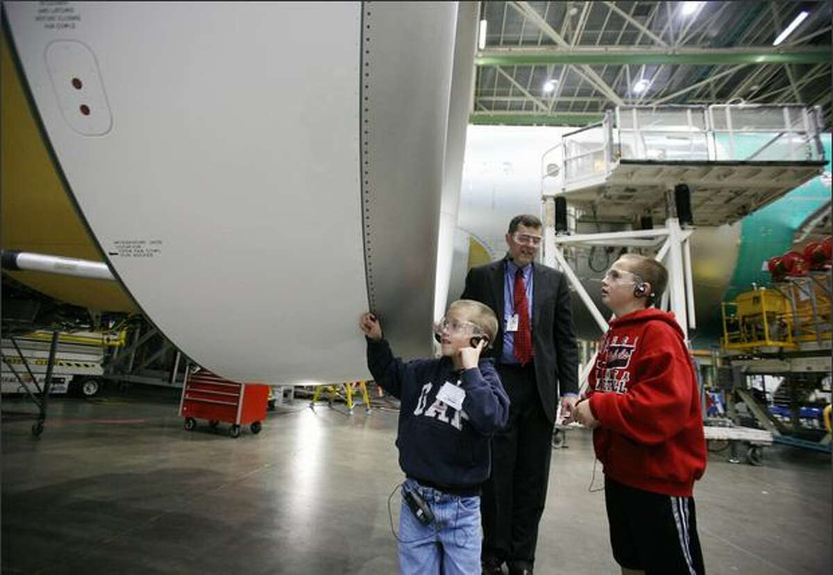 Reese, senior manager for Boeing Everett visitor relations, leads Adam, 7, and Michael Petter, 11, on a VIP tour of Boeing's Everett facility. The Petter's grandfather, Al Varness, was the three-millionth visitor to the plant, which earned them the VIP tour and this close-up look at one of a 777's engines.