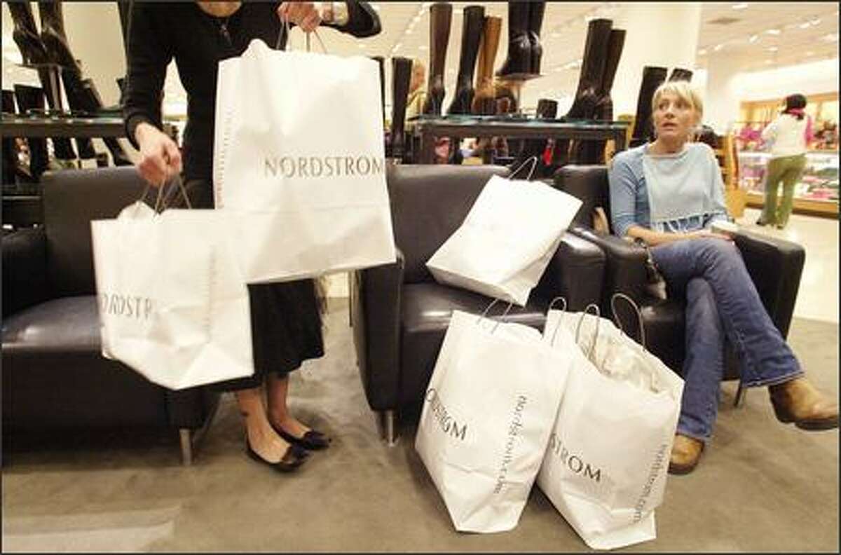 Nordstrom saleswoman Sara Jane Pignolet, left, helps shopper Ashley Hankins, right, gather her bags at the downtown Nordstrom store Tuesday.
