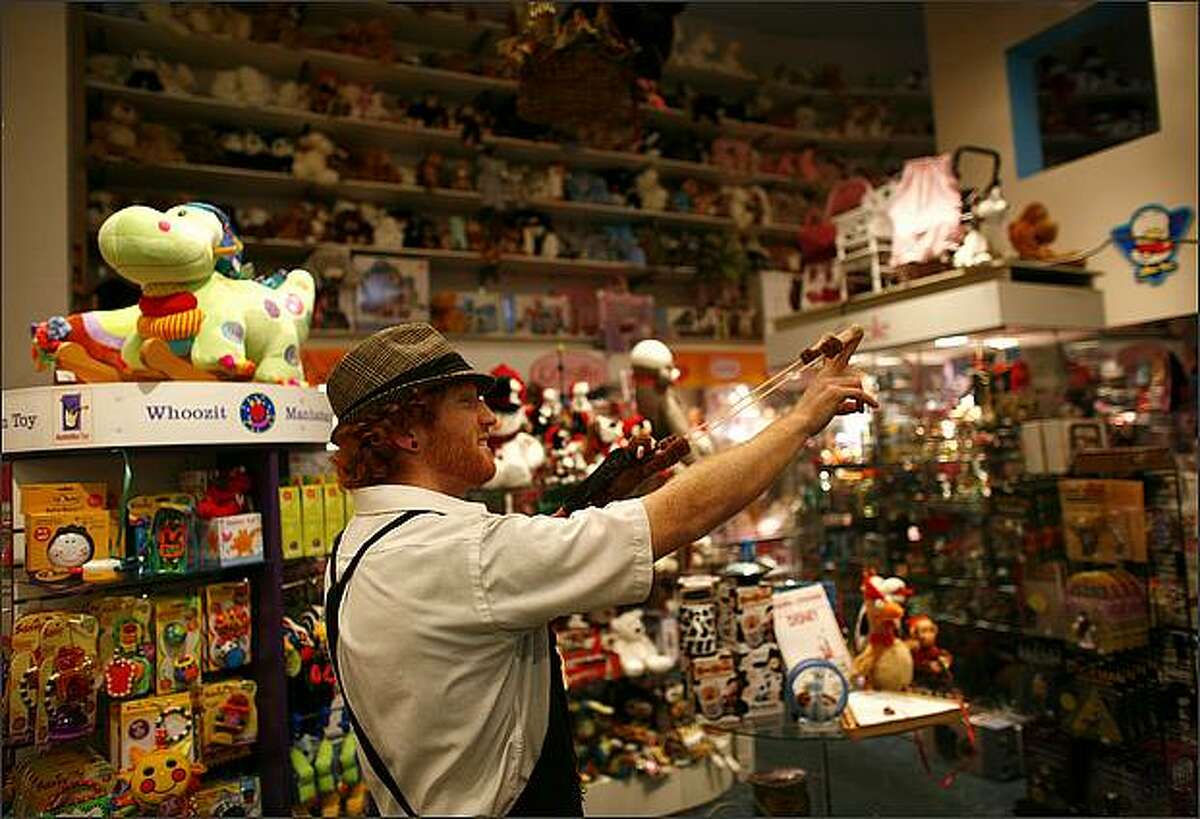 Kenny Whitebird, an employee of Magic Mouse Toys on 1st Avenue in Pioneer Square, prepares to launch a "flying monkey" across the toy store. Customers who enter the store are often greeted by the "flying monkeys" or animated toy animals walking across the floor.