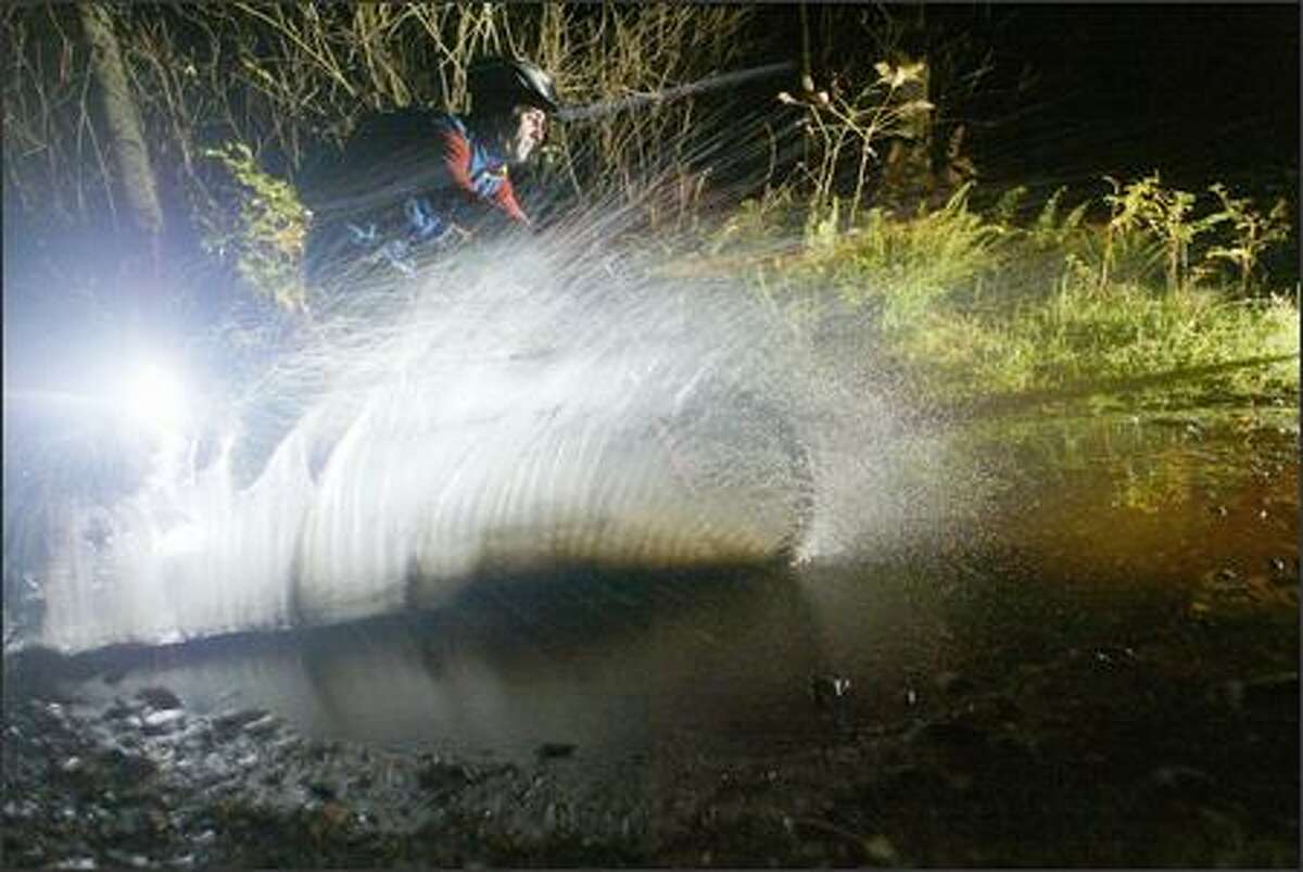 Doug Nathe plows through a mud puddle during a night mountain-bike ride near Fall City.