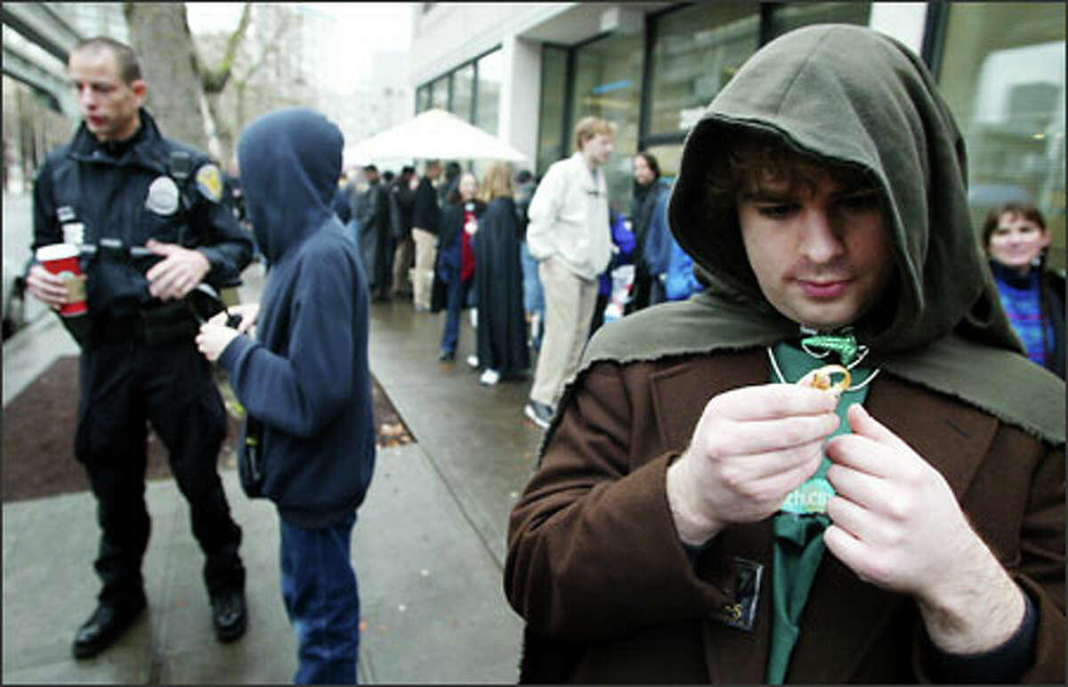 Self-described "Lord of the Rings" fanatic Casey Jepson, dressed as hobbit Frodo Baggins, admires his precious "One Ring" while waiting in line to enter the Cinerama in downtown Seattle. The theater plans to show the first two movies in the Lord of the Rings trilogy and then cap the evening with a 10 p.m. premiere of the new movie, "The Return of the King." One fan said he was in line since Saturday morning.