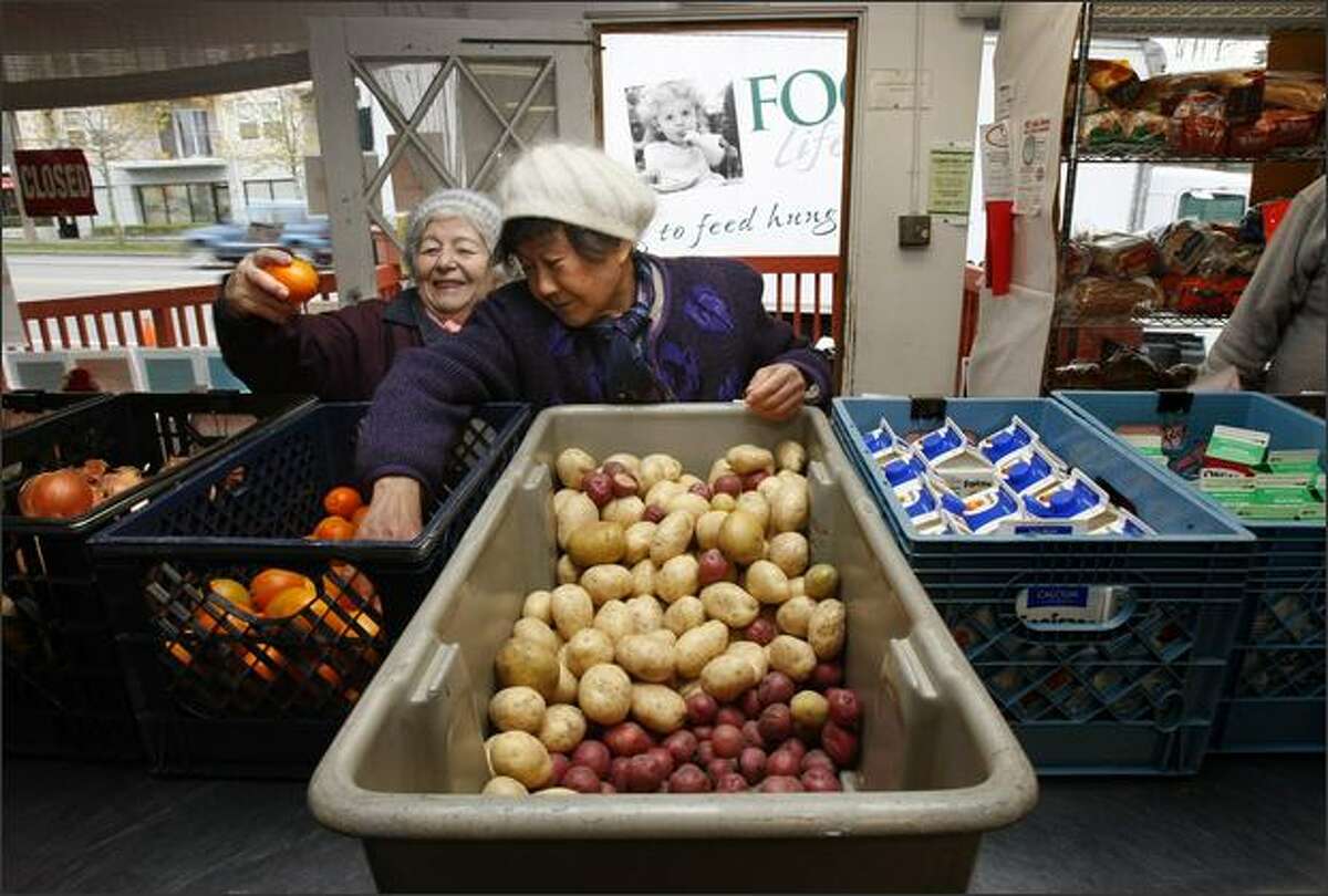 Maria Aklipi, left, and Shufang Dang sift through produce offered at the Volunteers of America Greenwood Food Bank.