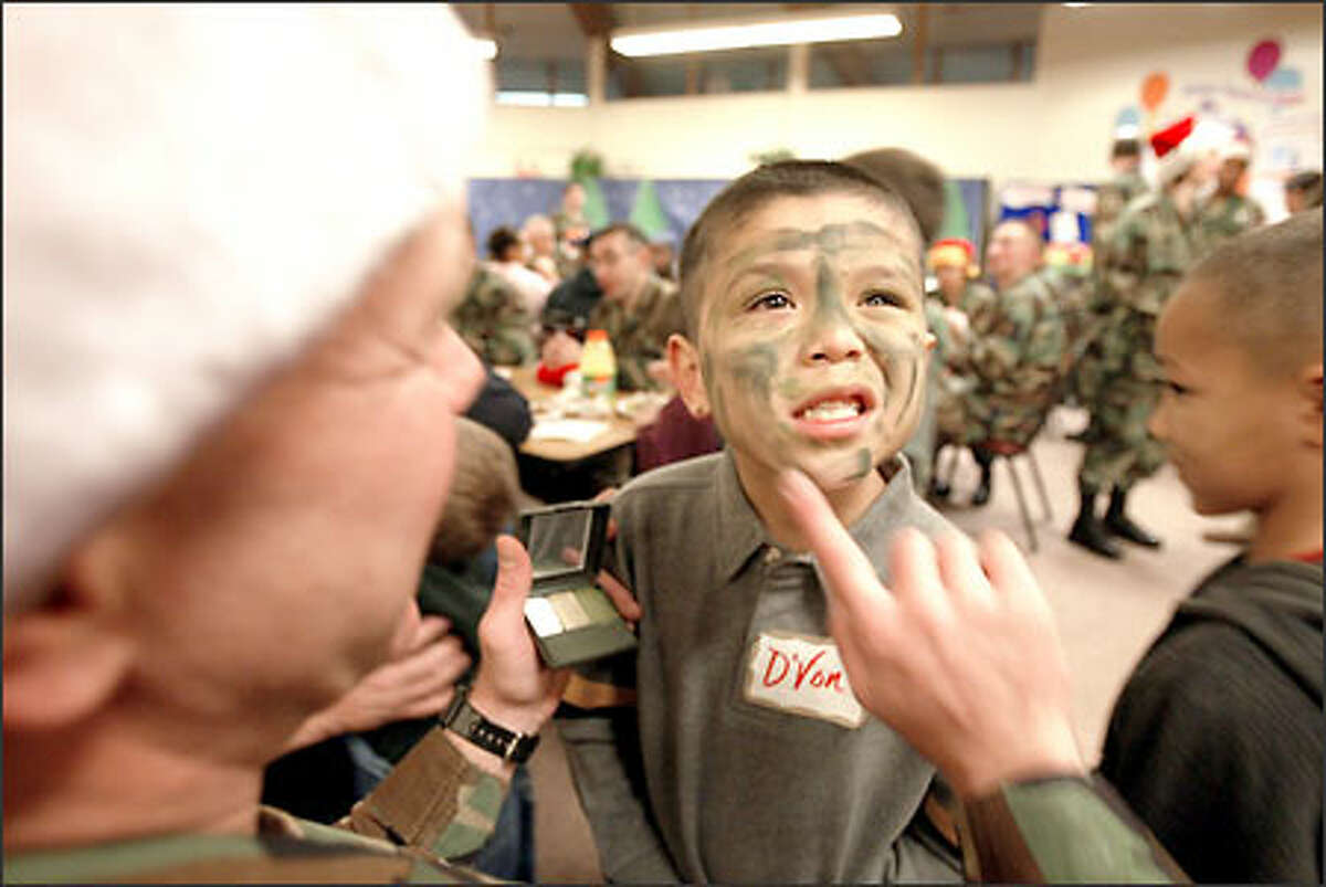 D'Von Harrison, 6, although not a student at Eugene P. Tone School, is on hand to get a camouflage look courtesy of Sgt. Maj. Tony Cady. D'Von is a student at McCarver Elementary and lives in shared housing with his mother.