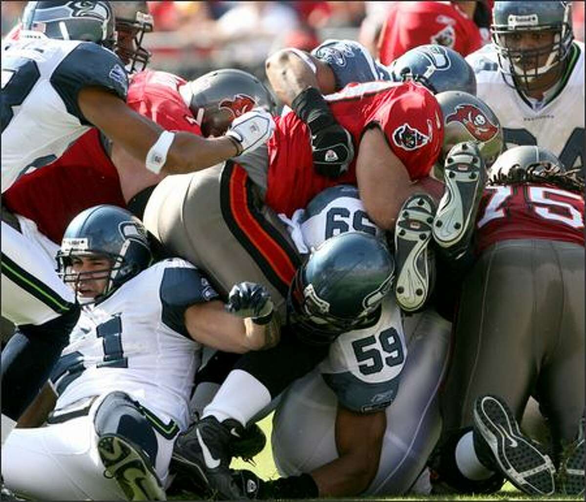 The Seahawks defense gang-tackles Mike Alstott for no gain in the first quarter of Sunday's game against the Tampa Bay Buccaneers. Seattle won 23-7.